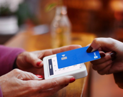 Pessoa aproximando cartão em uma máquina de pagamentos